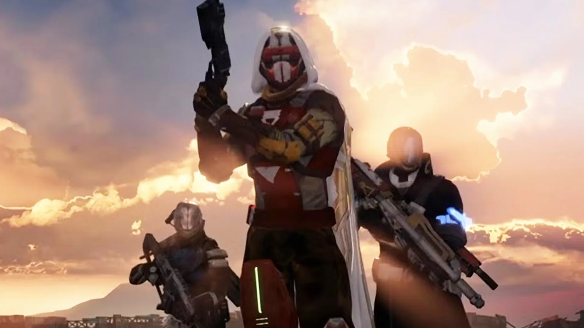 Tres guardianes de Destiny posan con su equipamiento frente a un cielo al atardecer.