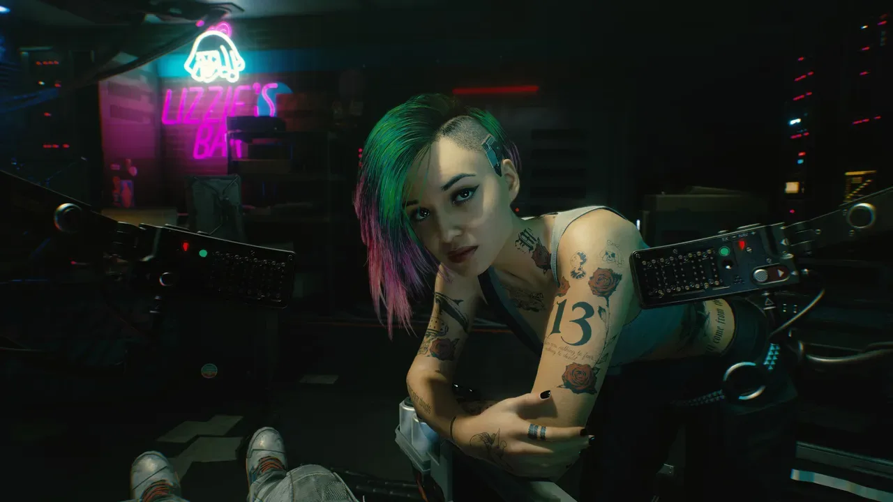 Judy Álvarez en una escena de Cyberpunk 2077, con el neón de Lizzie's Bar al fondo.