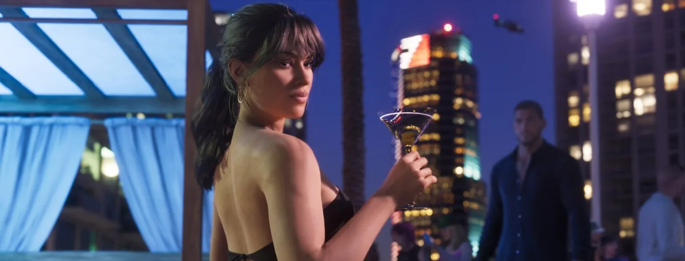 Lucia sosteniendo una copa de cóctel en una terraza nocturna, escena del tráiler de Grand Theft Auto VI.